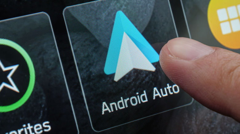 Finger touching the Android Auto logo in the car infotainment screen