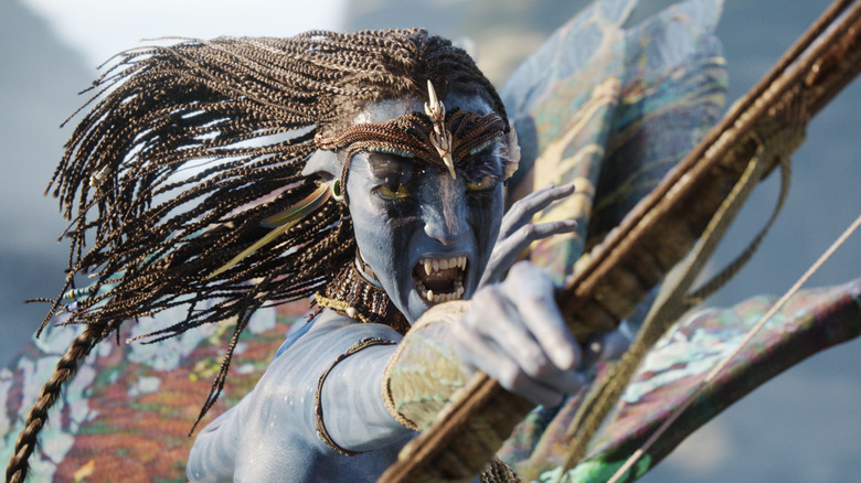 Zoe Saldaña as Neytiri yelling with her bow in hand heading into battle in Avatar: Fire and Ash