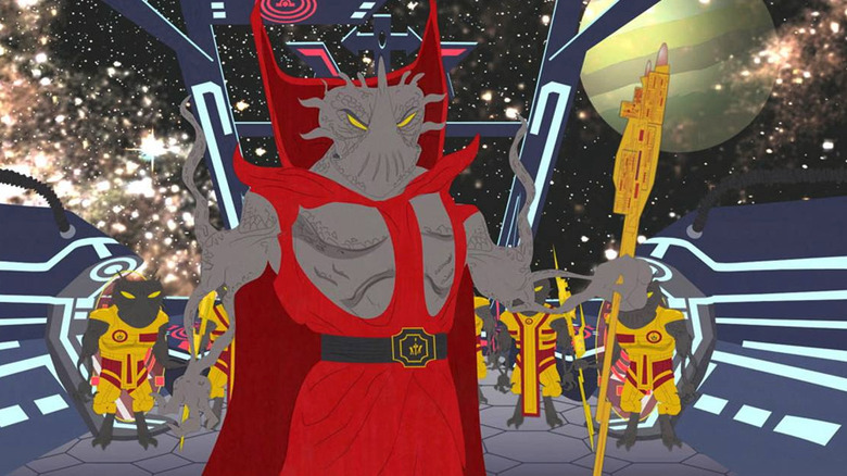 Alien conqueror Xenu wears a red robe while standing aboard a spaceship with his alien henchmen stand behind him in 