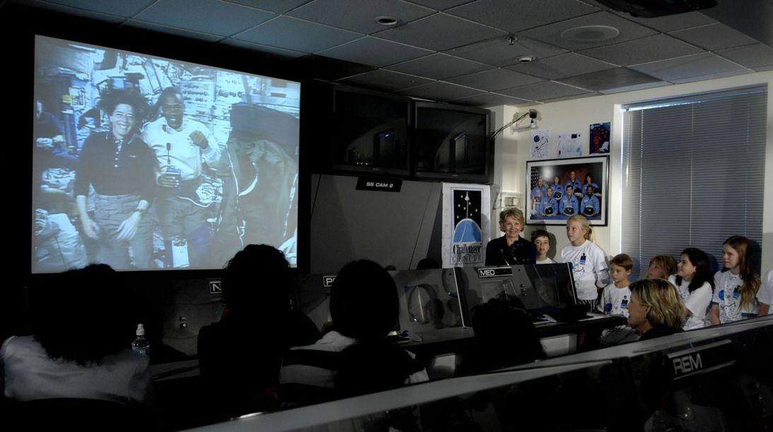 Dr. June Scobee Rodgers, founder of the Challenger Center, greets astronauts Barbara Morgan and Benjamin Drew Jr. during a live downlink for students at the center on August 16, 2007.