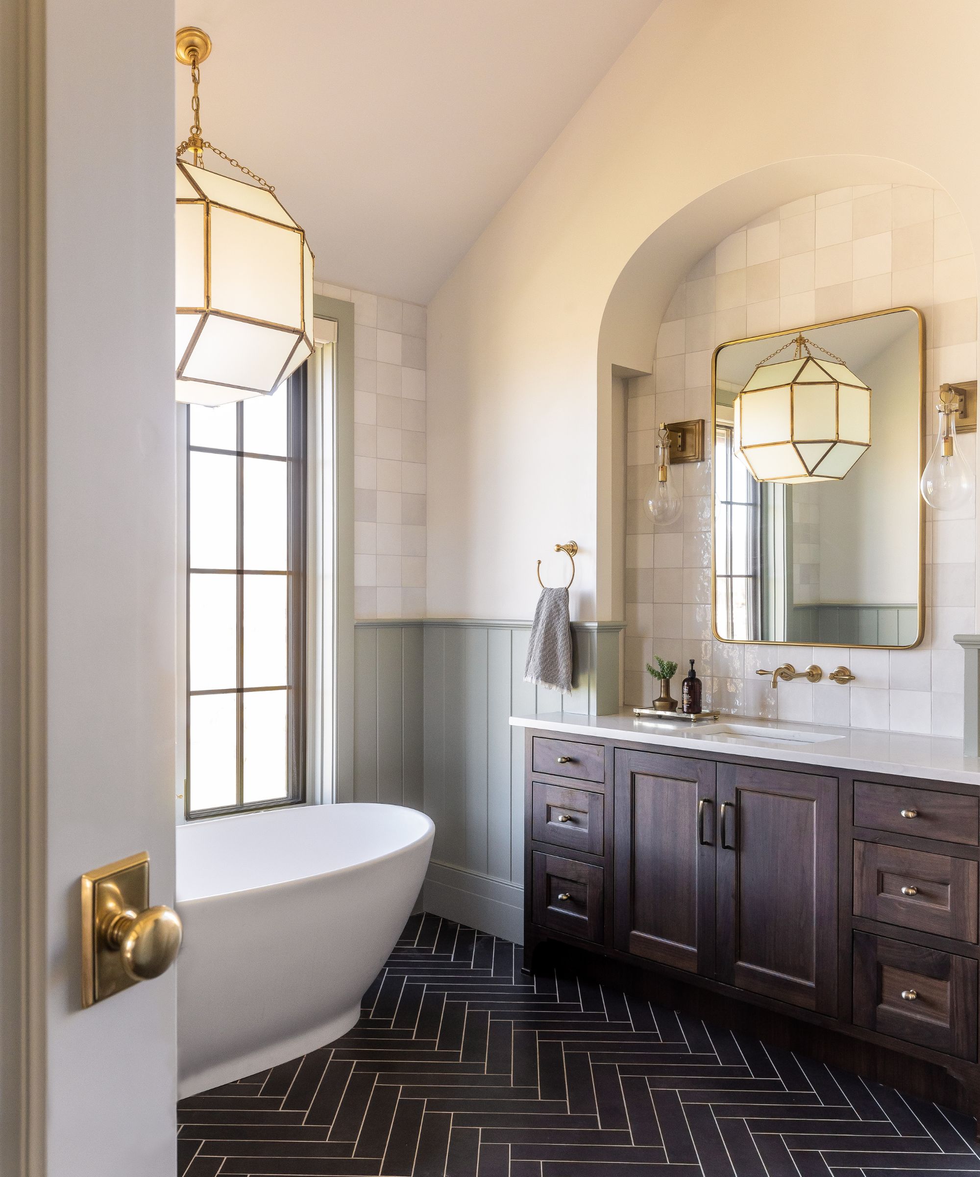 A warm neutral bathroom with light green paneling and a wooden vanity