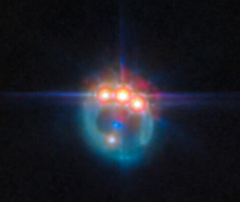 A colorful astronomical object revealed by JWST, with several bright lights arranged in a semicircle against a black background, resembling a glowing paw print in the vast universe.