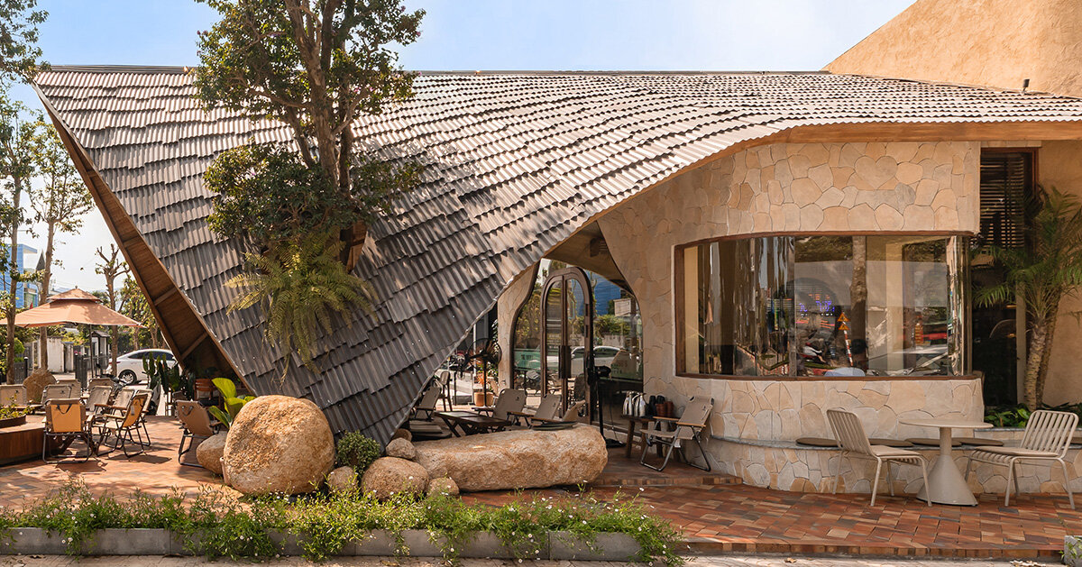 rippling metal roof drapes over interlocking stone volumes of vietnamese café