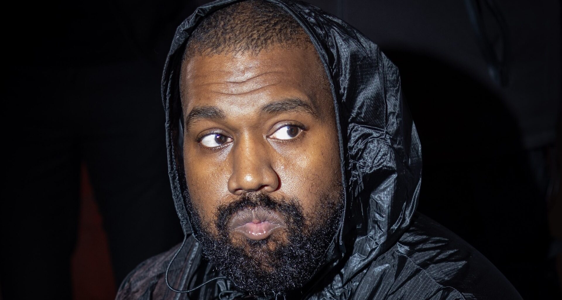 Kanye West wearing a black hooded jacket.