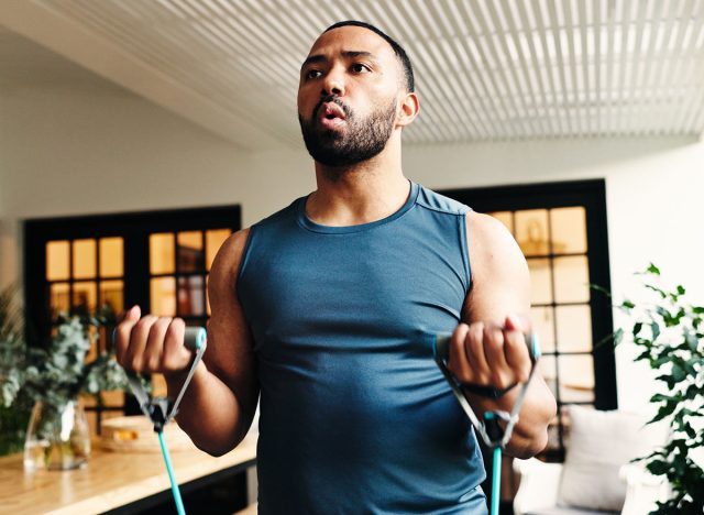 Fitness, man and resistance band for bicep exercise, strength and breathing for power in home. Equipment, muscle curls and person stretching for training, workout arms and bodybuilding for health