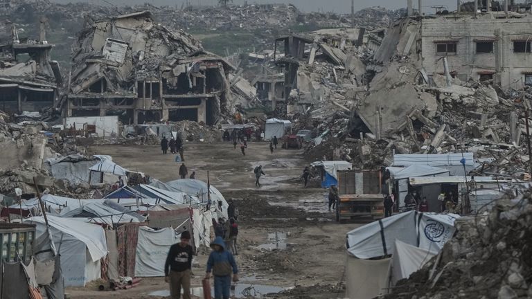 Palestinians walk amid buildings destroyed by Israeli air and ground operations in Gaza. Pic: AP