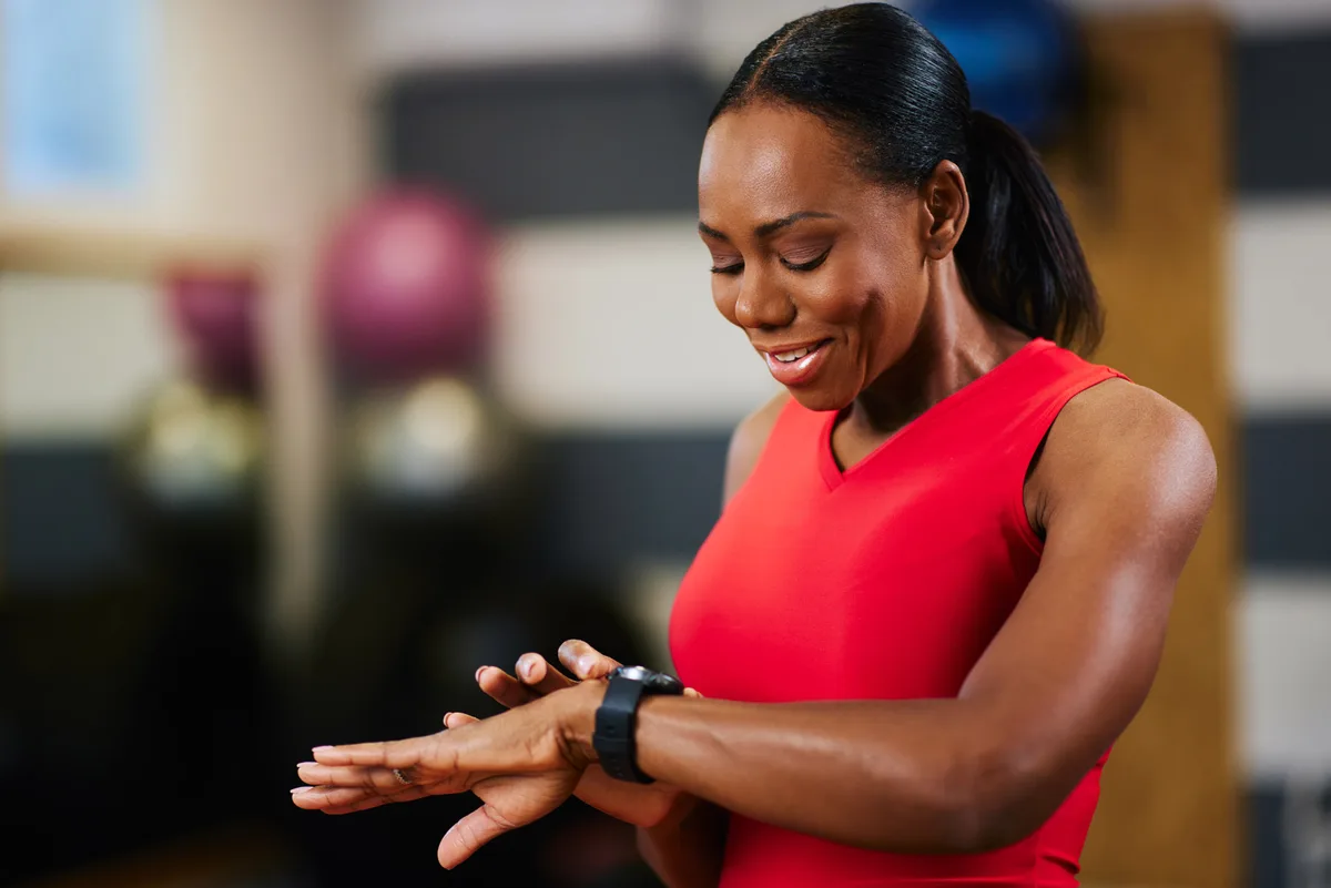 Woman checking fitness tracker during workout at gym