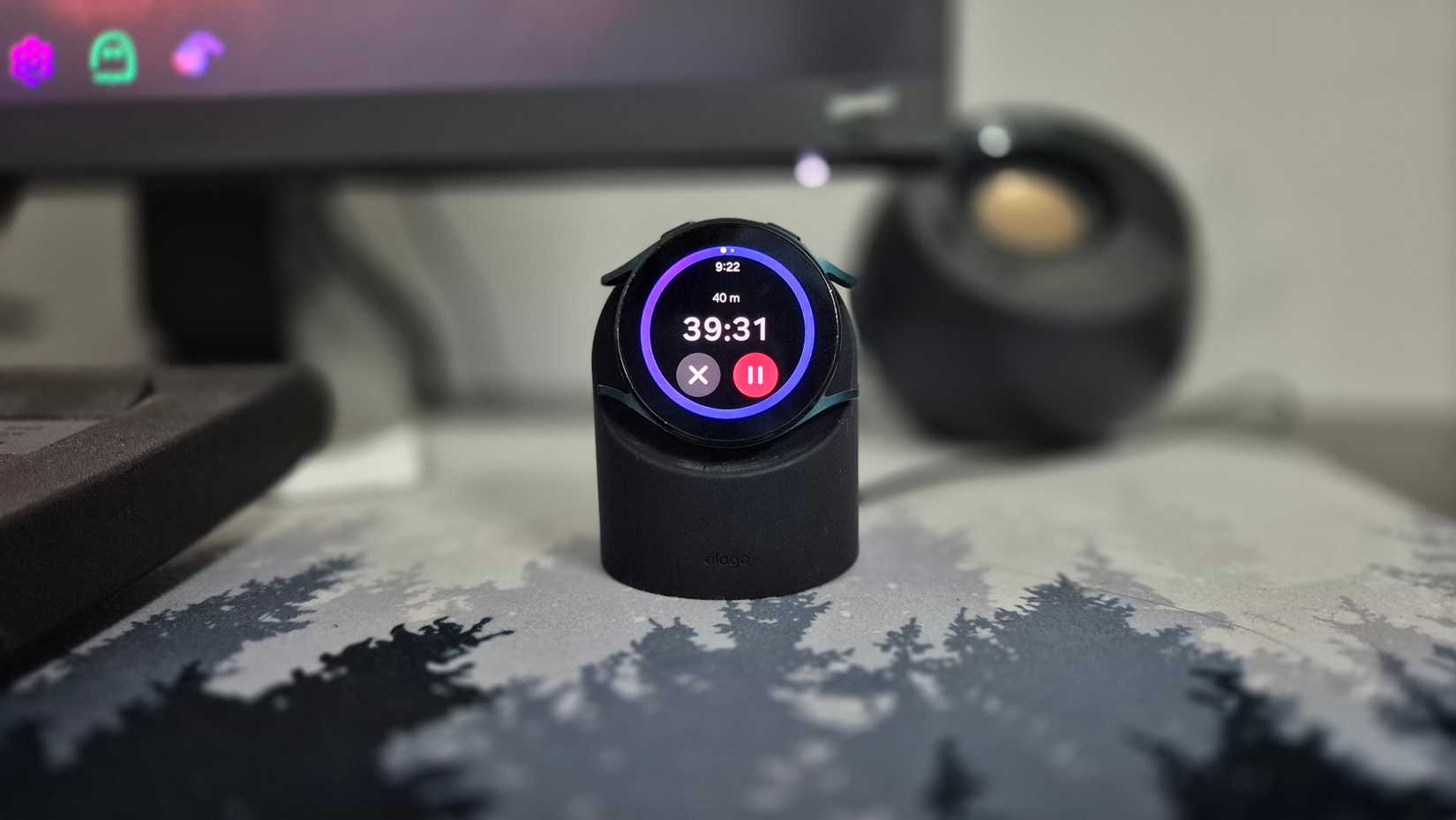 The Samsung Galaxy Watch 4 as a desk clock on an upright charging mount.