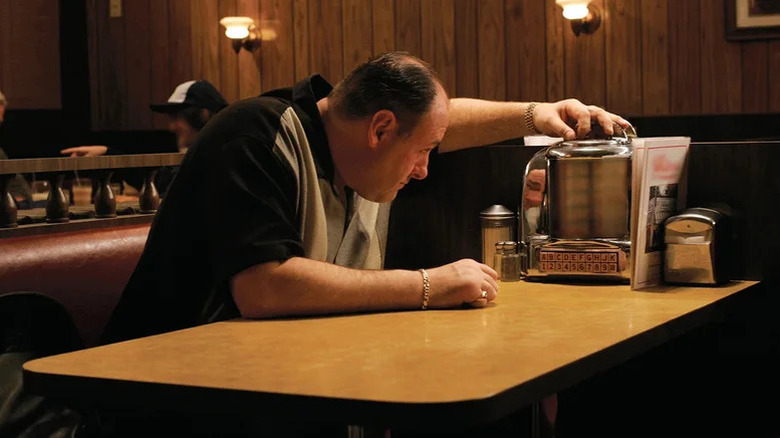James Gandolfini's Tony Soprano sitting at a restaurant table and inspecting an object on The Sopranos