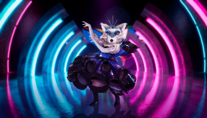 ©ITV Plc Someone dressed as an Arctic Fox in a dress, raising their arms to one side.