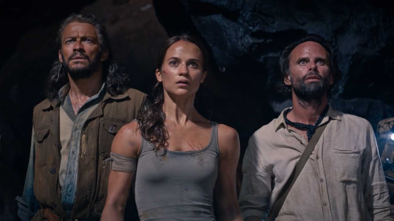 Dominic West, Alicia Vikander, and Walton Goggins, lined up in a row, gaze in awe at, what else, a particularly elaborate tomb (off screen), in a scene from the 2018 version of Tomb Raider. 