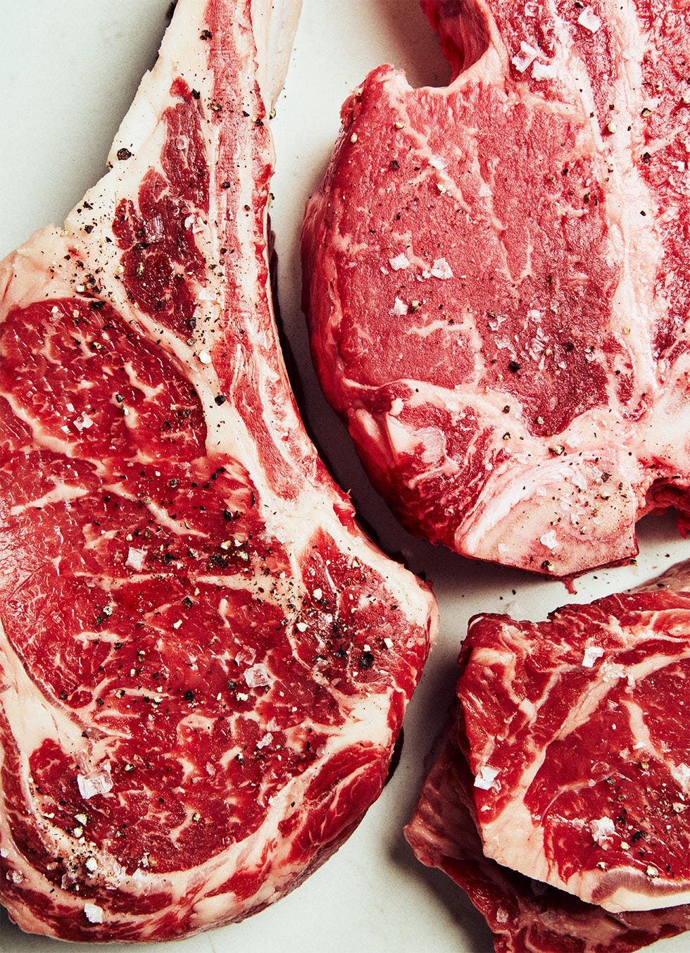 three raw steaks with salt and pepper on them three raw steaks with salt and pepper on them