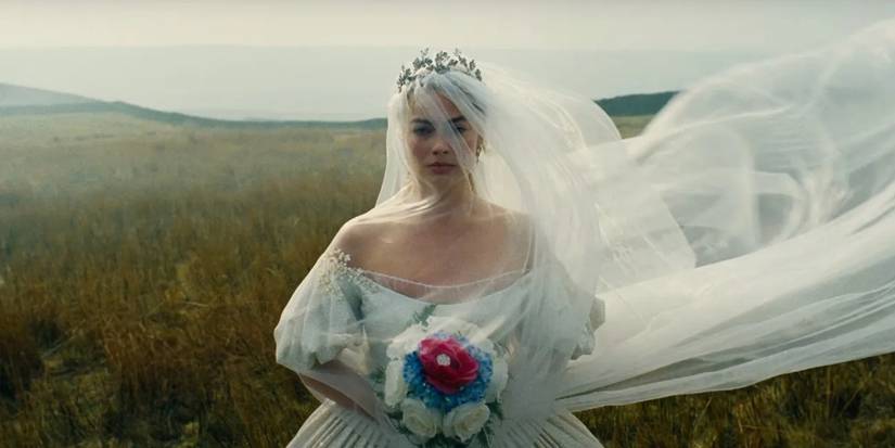 Margot Robbie as Catherine walking in a field in a wedding dress in Wuthering Heights