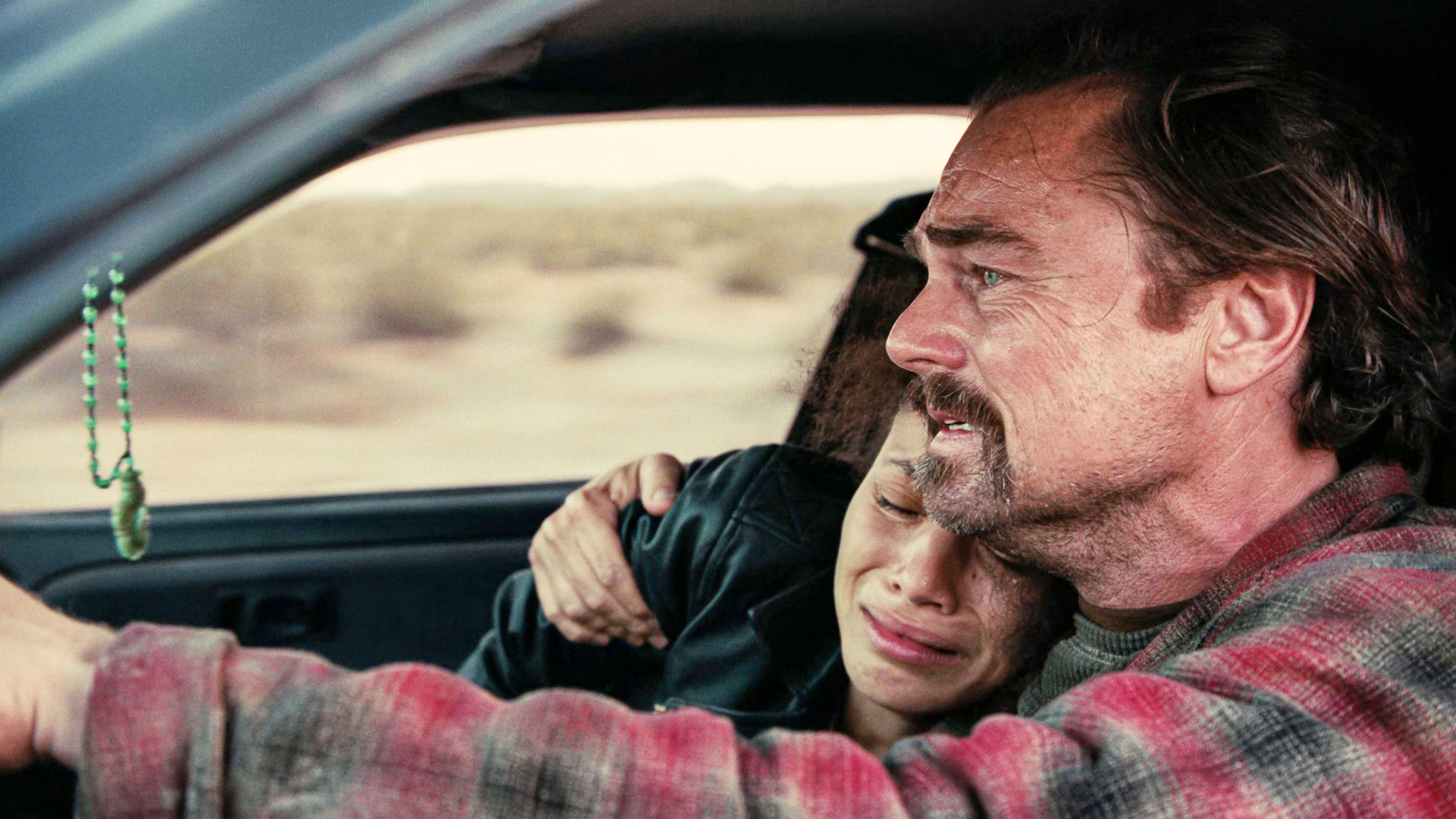 Leonardo DiCaprio driving, with Chase Infiniti crying and hugging him in a car.