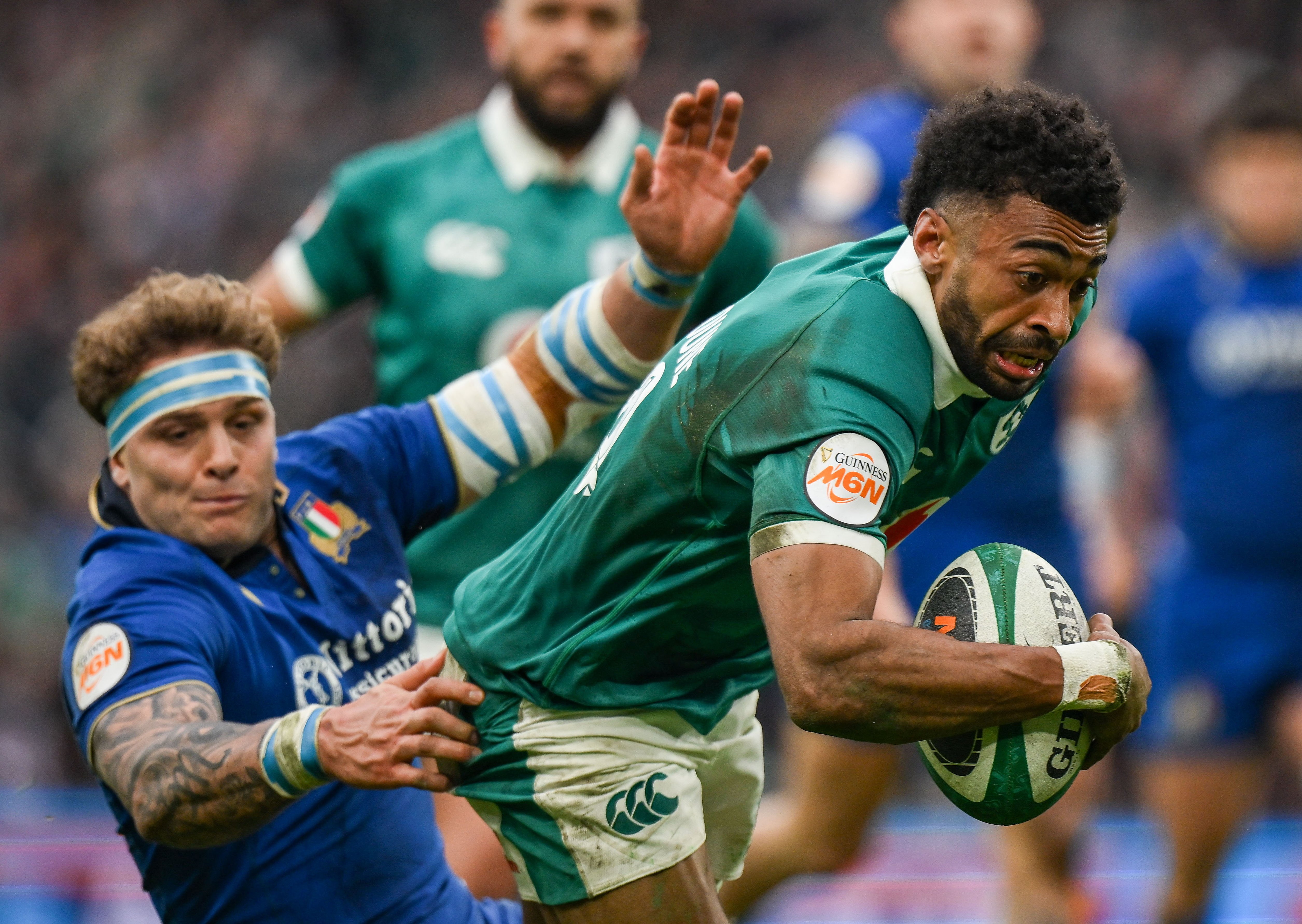 Robert Baloucoune of Ireland dives to score a try while being tackled by Lorenzo Cannone of Italy during a rugby match.
