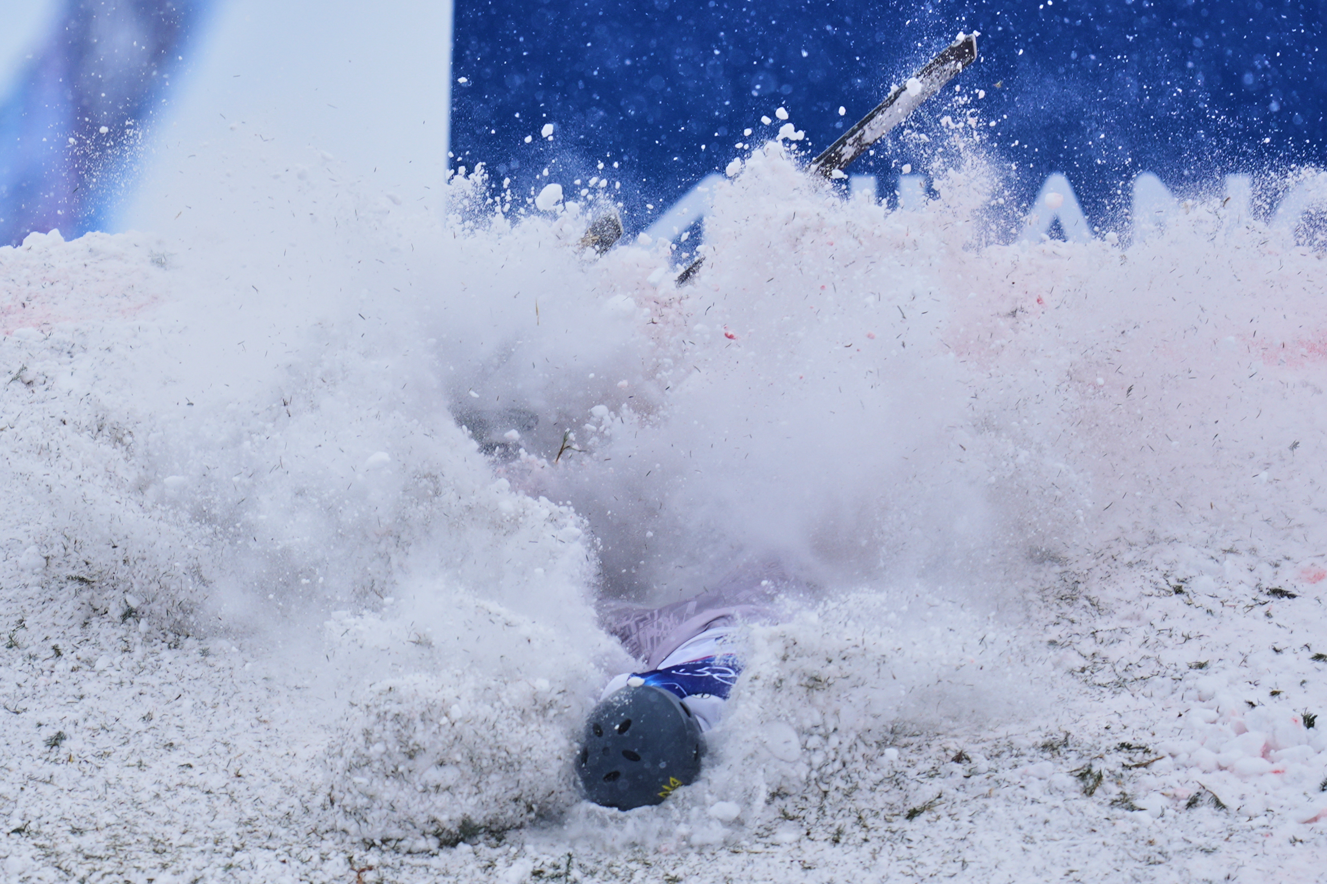 Ukraine's Maksym Kuznietsov crashes during men's freestyle skiing aerials qualifications, surrounded by a cloud of snow and debris.