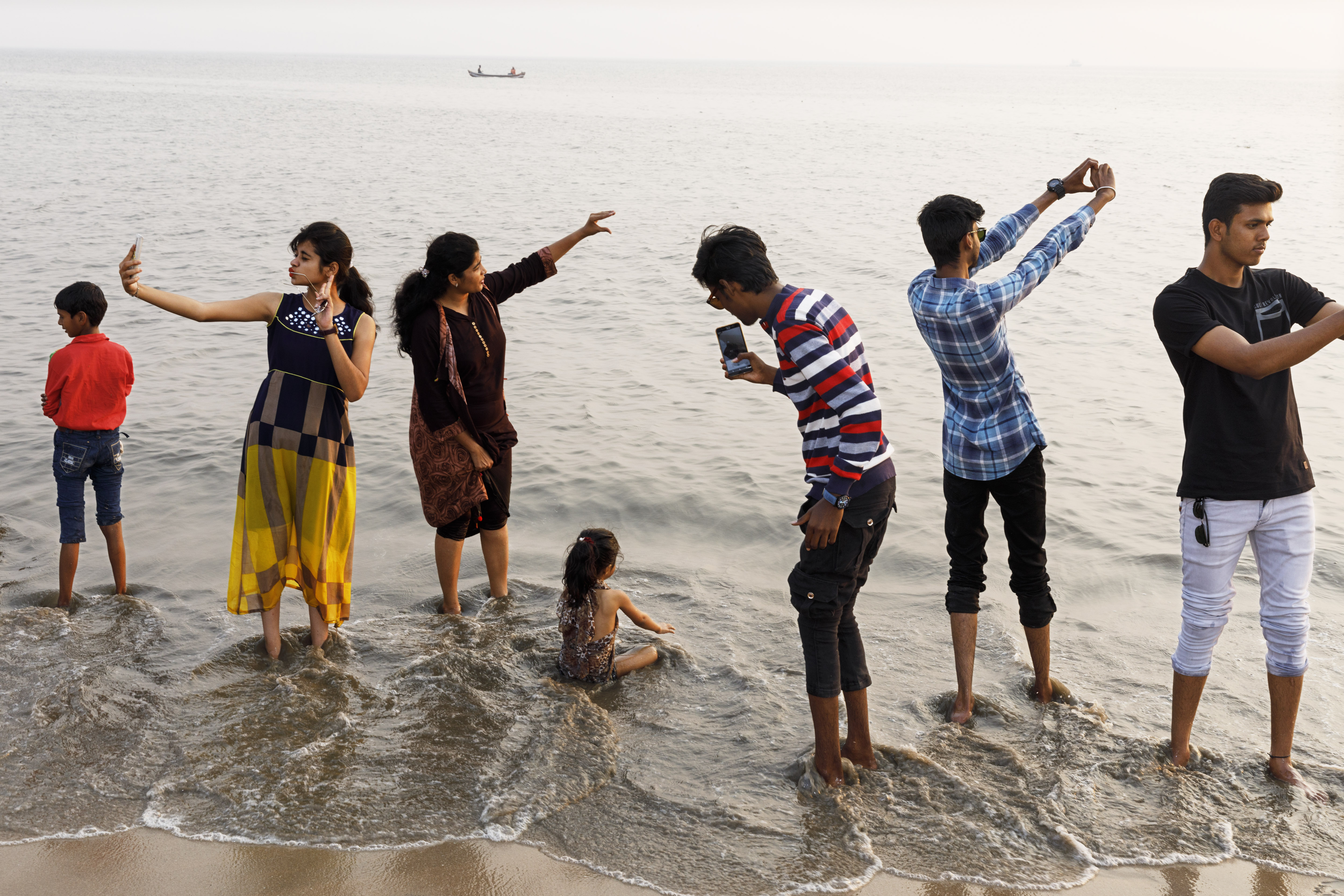 People on Chowpatty Beach, Mumbai, taking photos and enjoying the water.