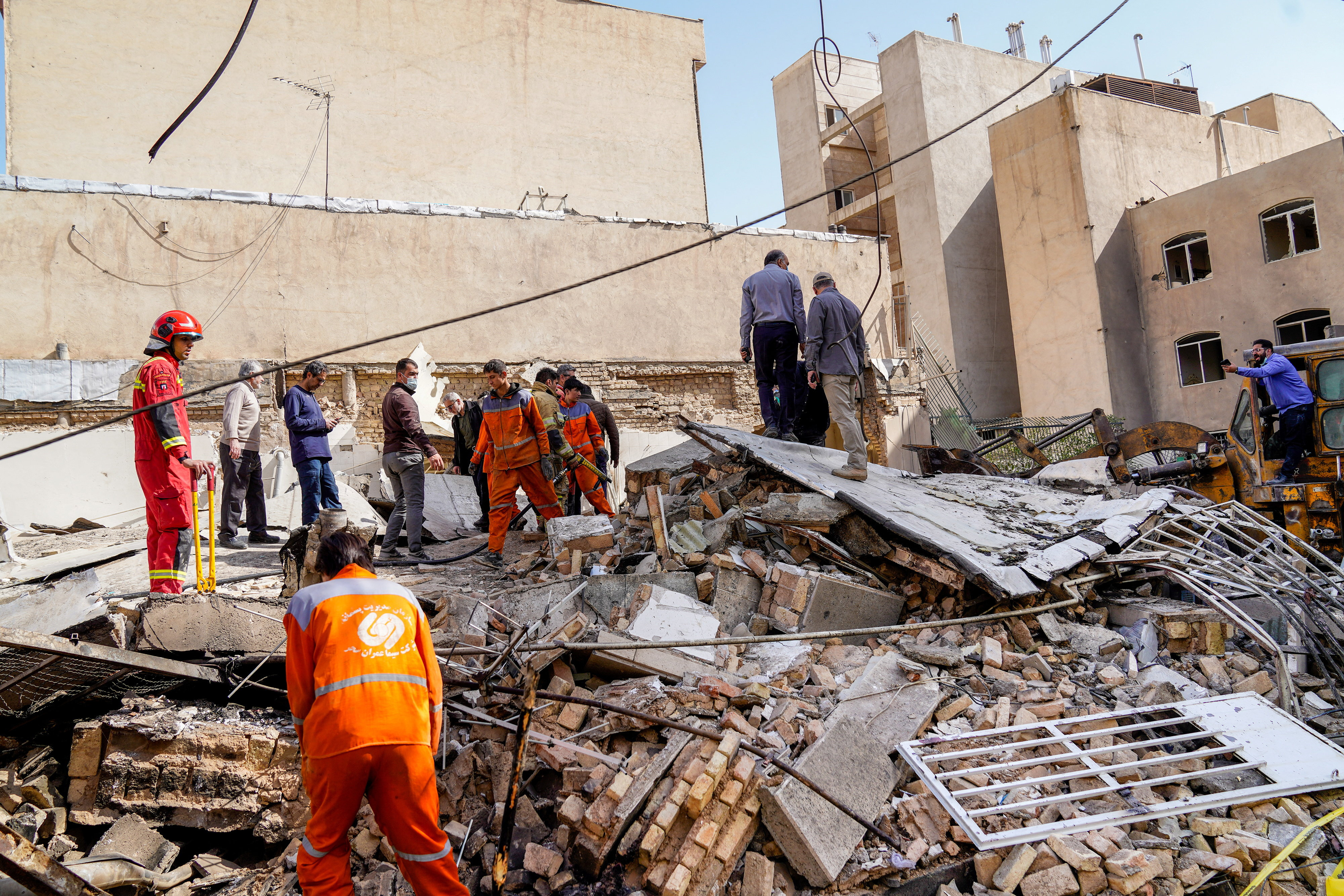 Rescuers and other individuals inspect the rubble of a damaged building in Tehran, Iran, after reported strikes.
