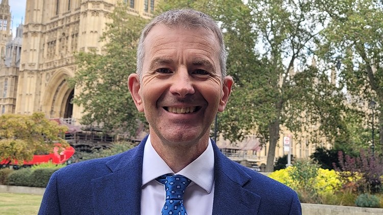 Professor Mark Mon-Williams smiling in front of a stone building and trees.