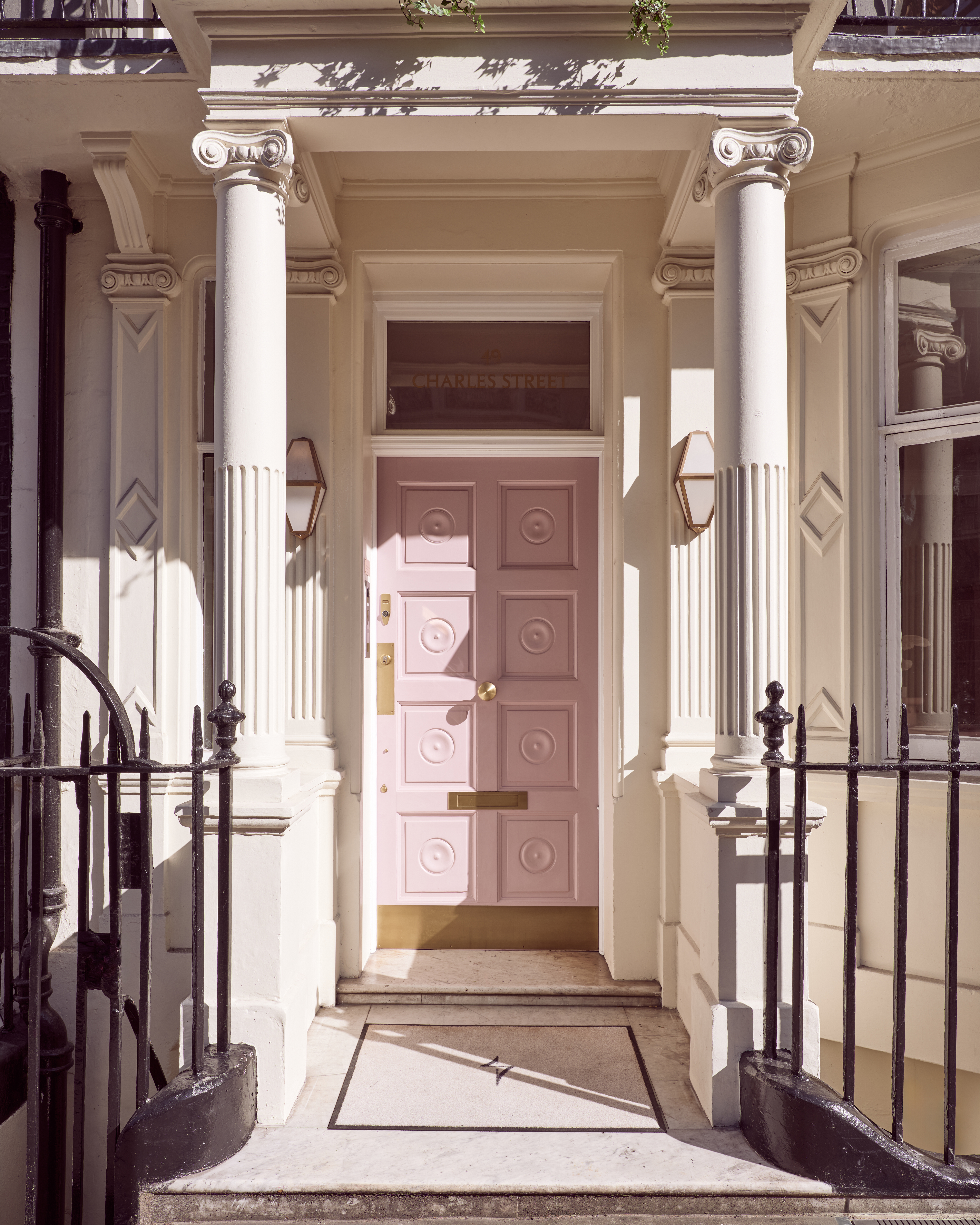 Front exterior of Dr. Joseph's clinic, featuring a pink door with gold hardware, white pillars, and a black wrought-iron railing.