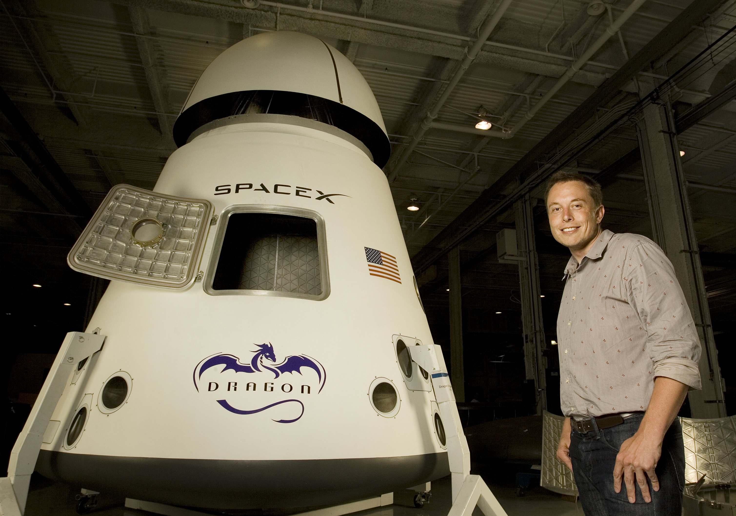 Elon Musk standing next to a SpaceX Dragon spacecraft.