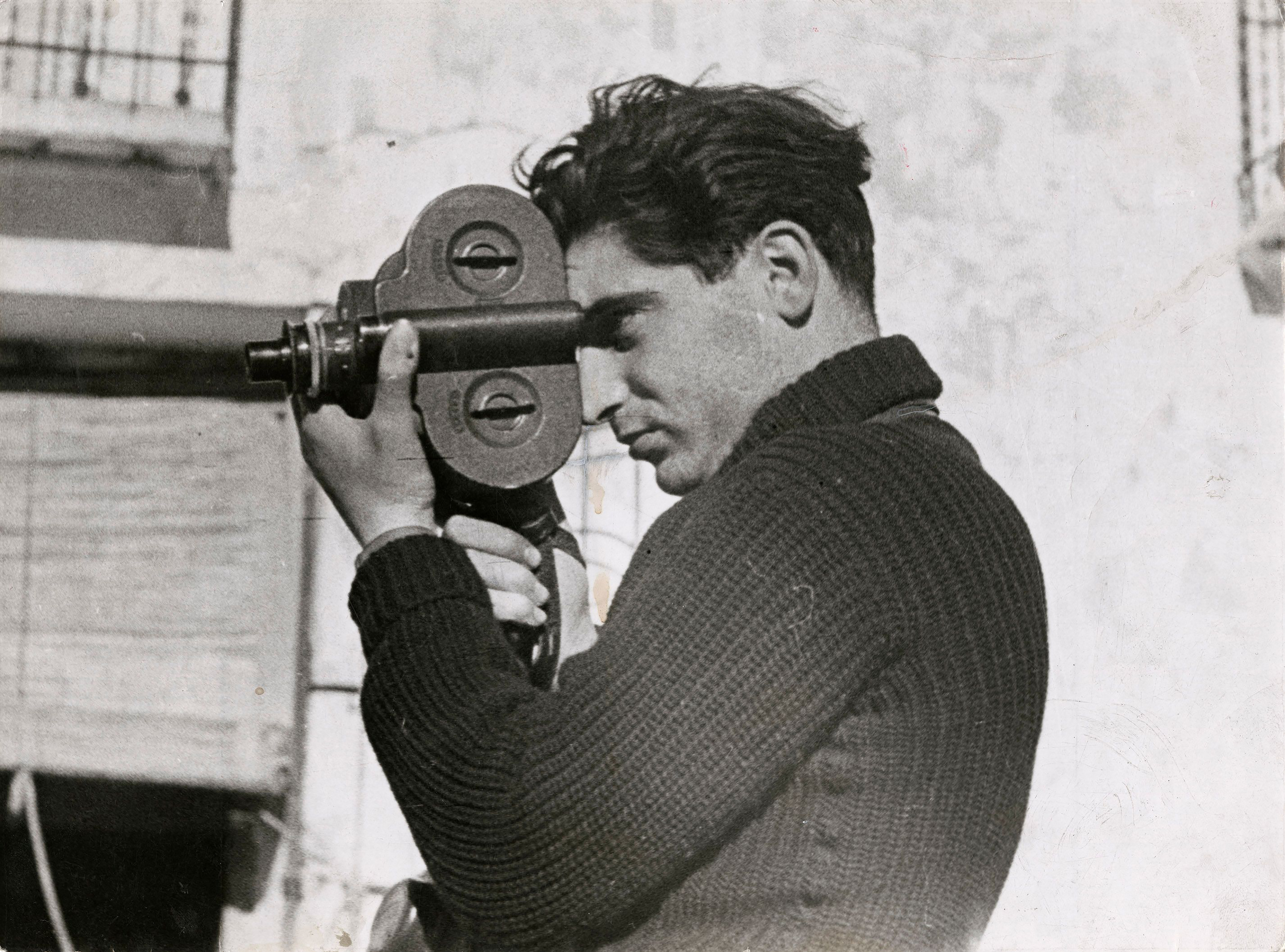 Robert Capa looking through a camera viewfinder.