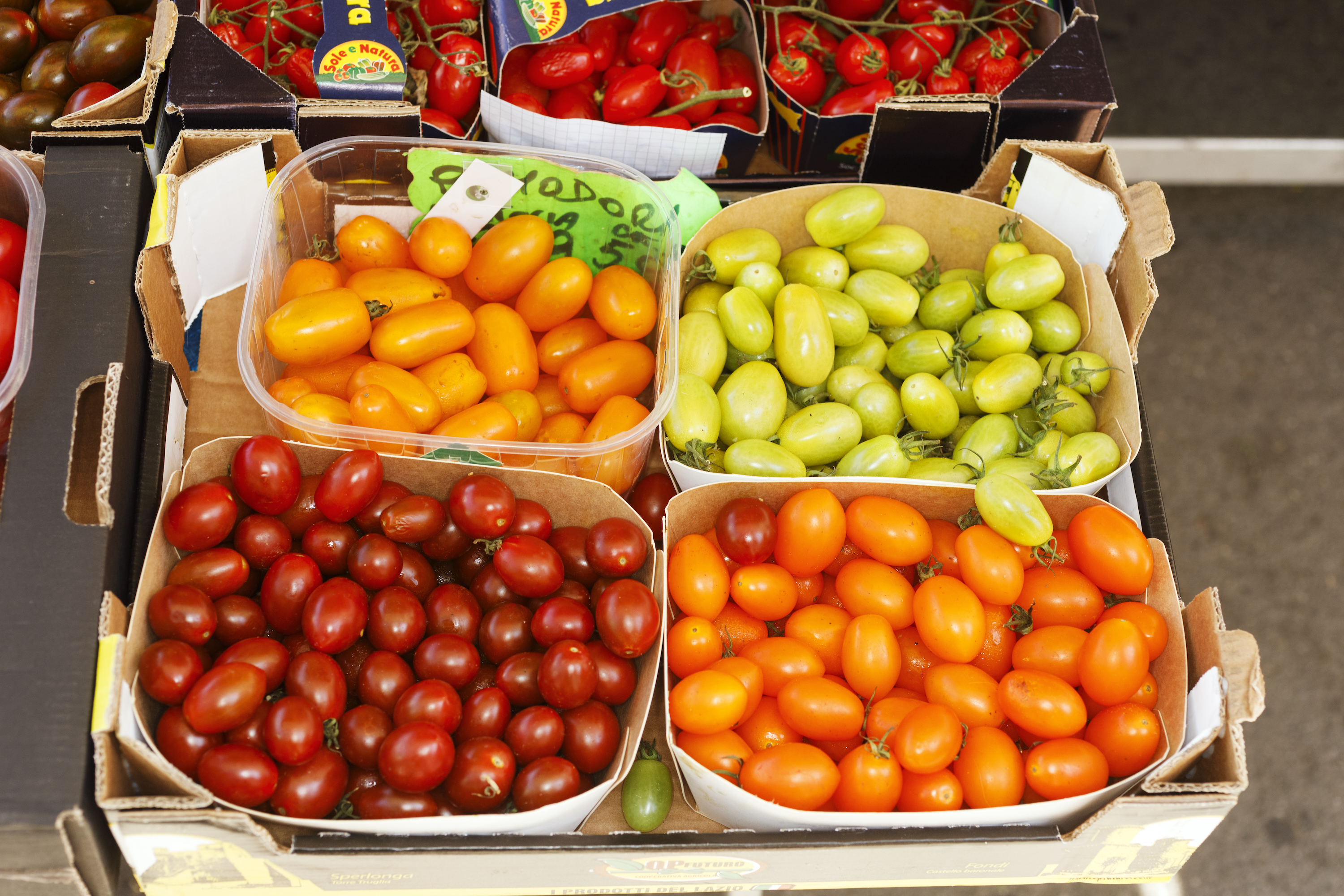 Four different kinds of cherry tomatoes in various containers.