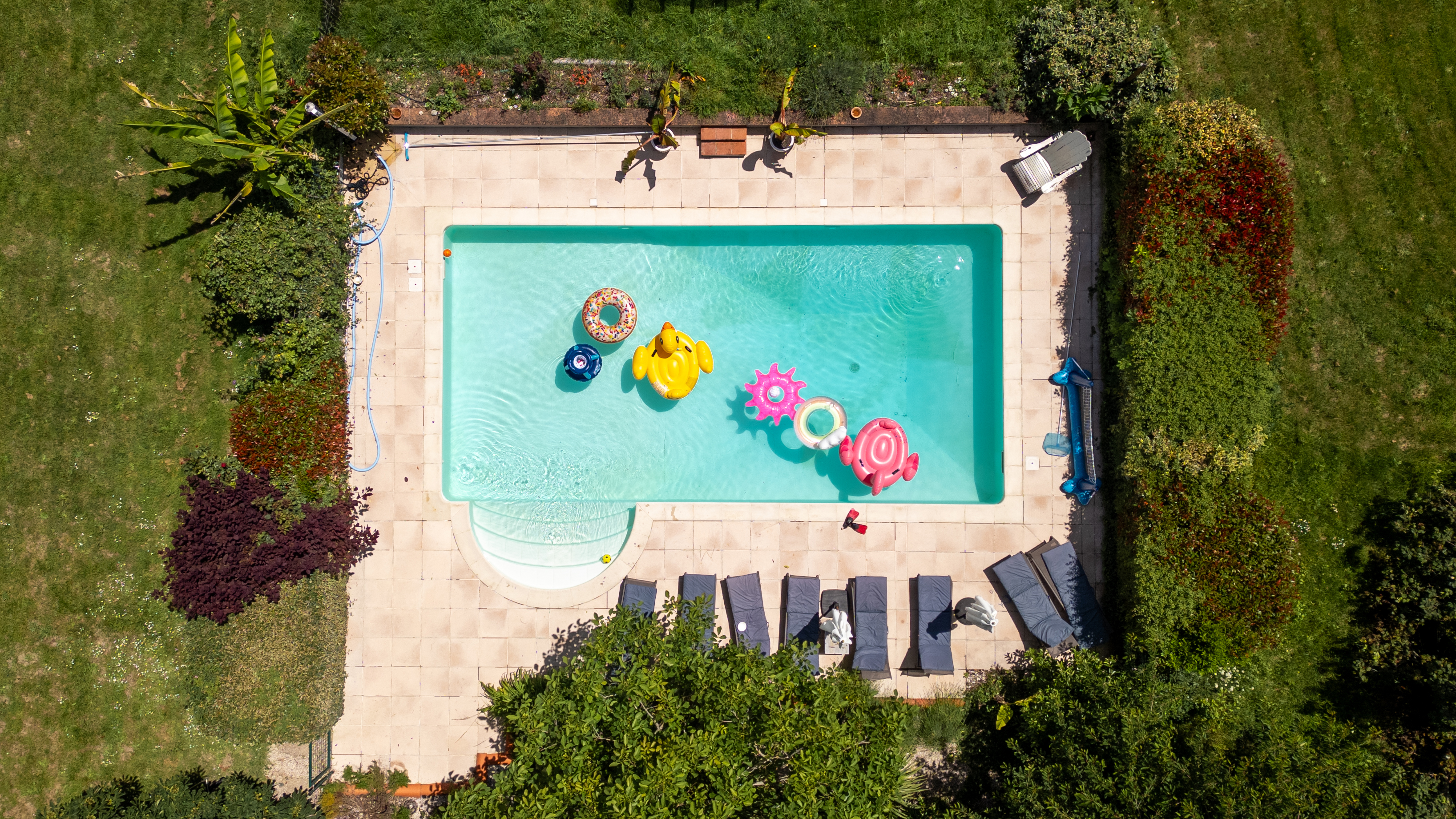Aerial view of a swimming pool with inflatables and sun loungers.