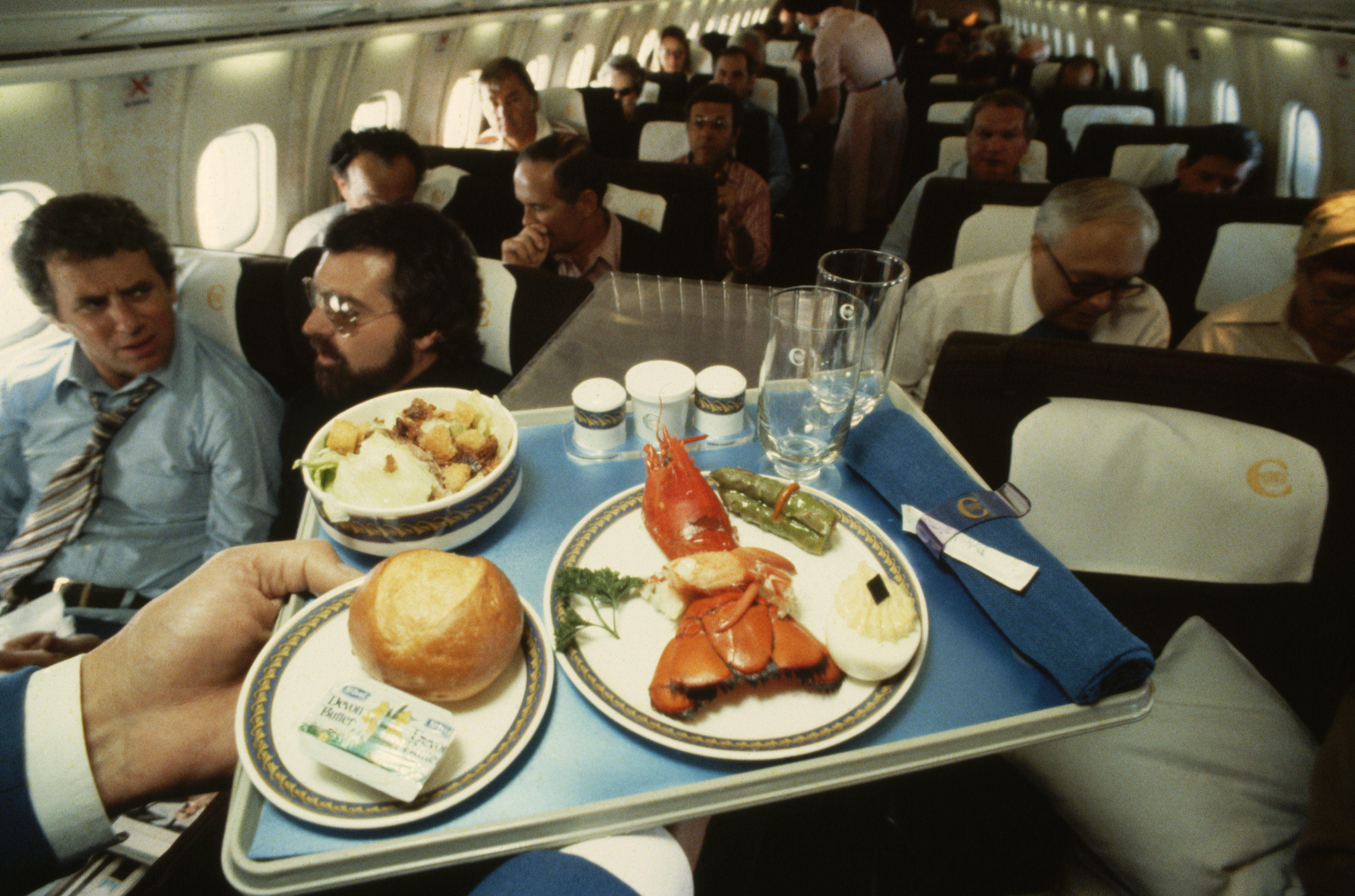 Meal on the Concorde with lobster, bread, salad, and drinks on a tray.