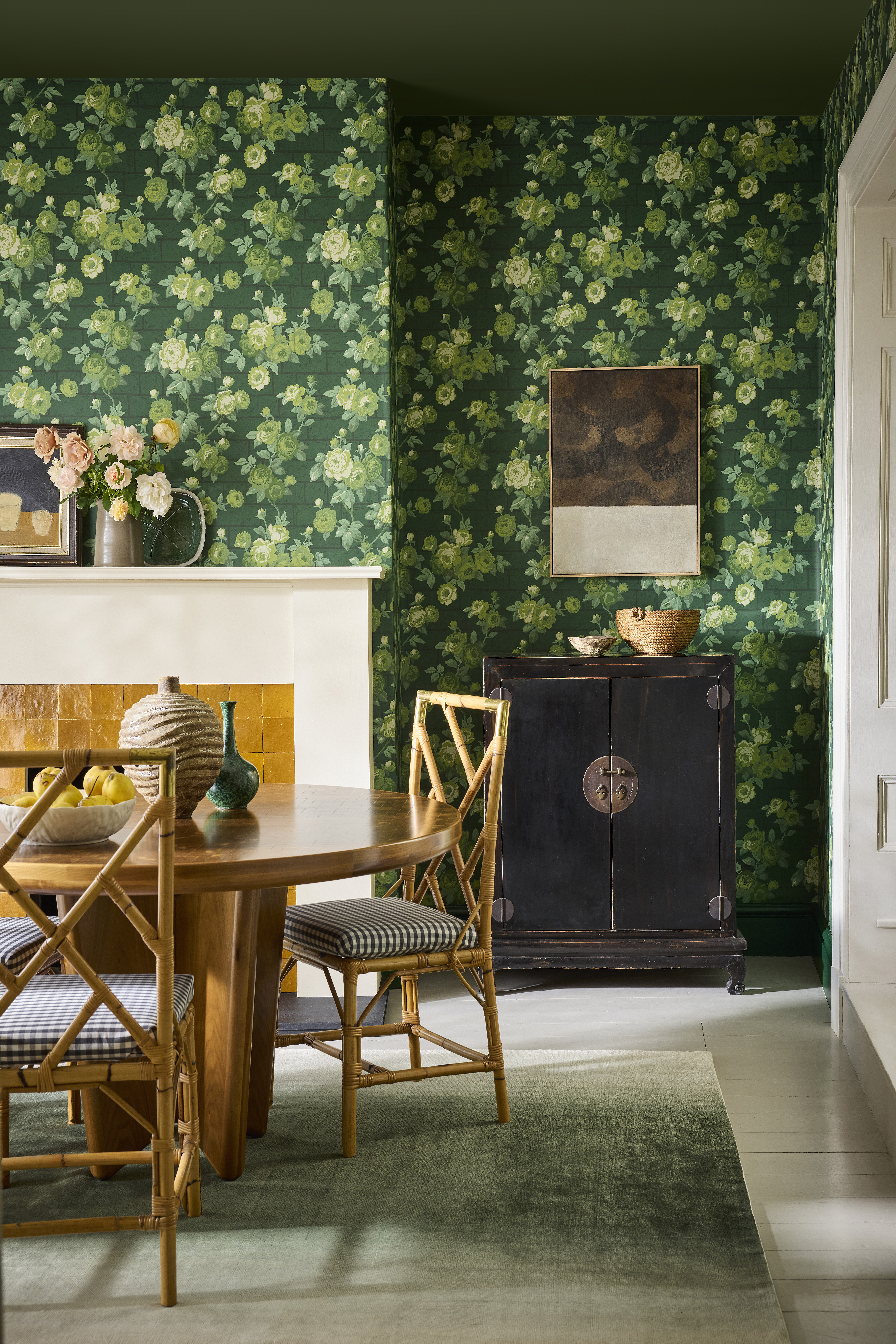 Dining room with green floral wallpaper, a wooden table, and bamboo chairs.