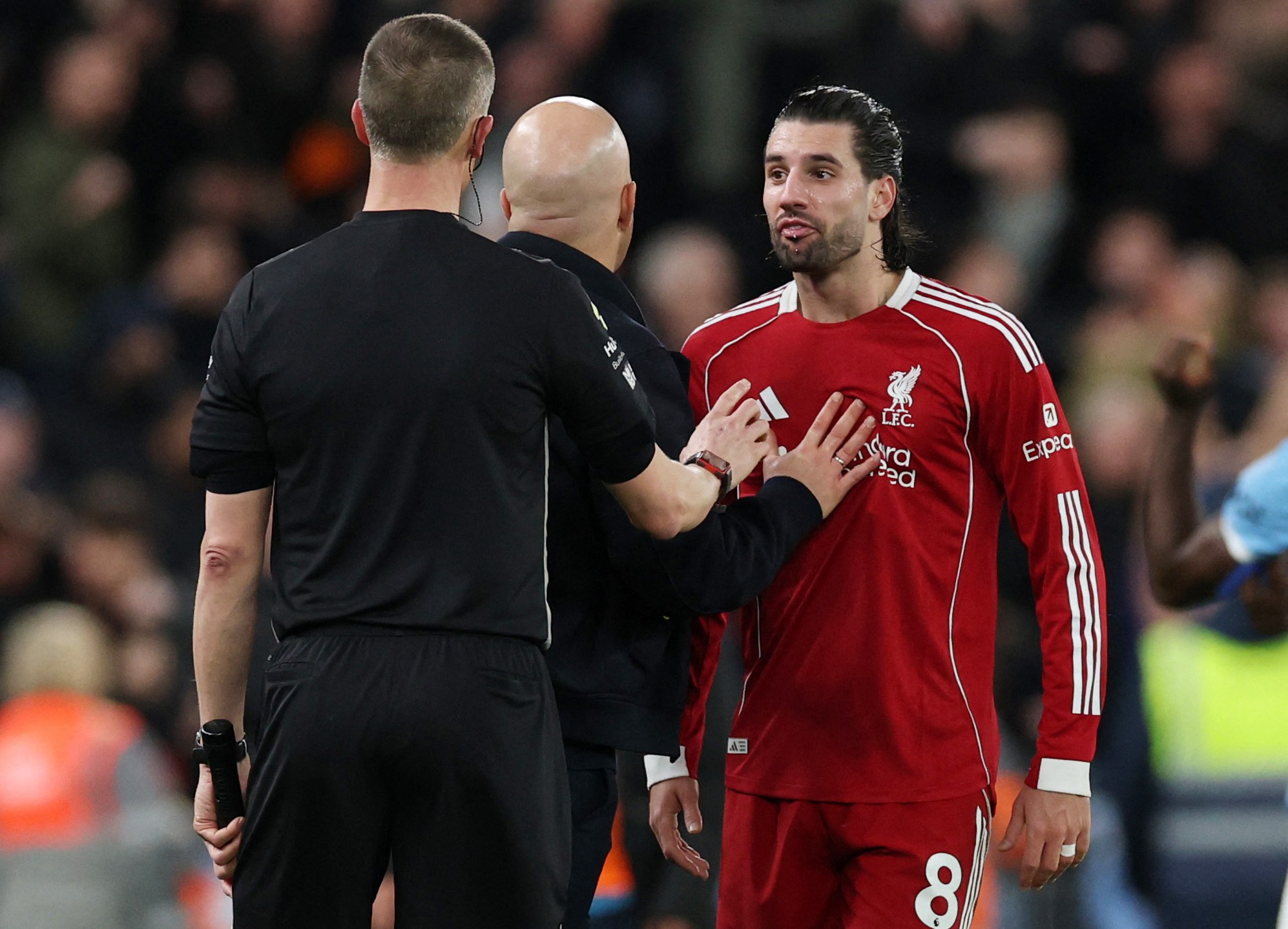 Liverpool player Dominik Szoboszlai reacting before being sent off upon VAR review, with manager Arne Slot looking on.