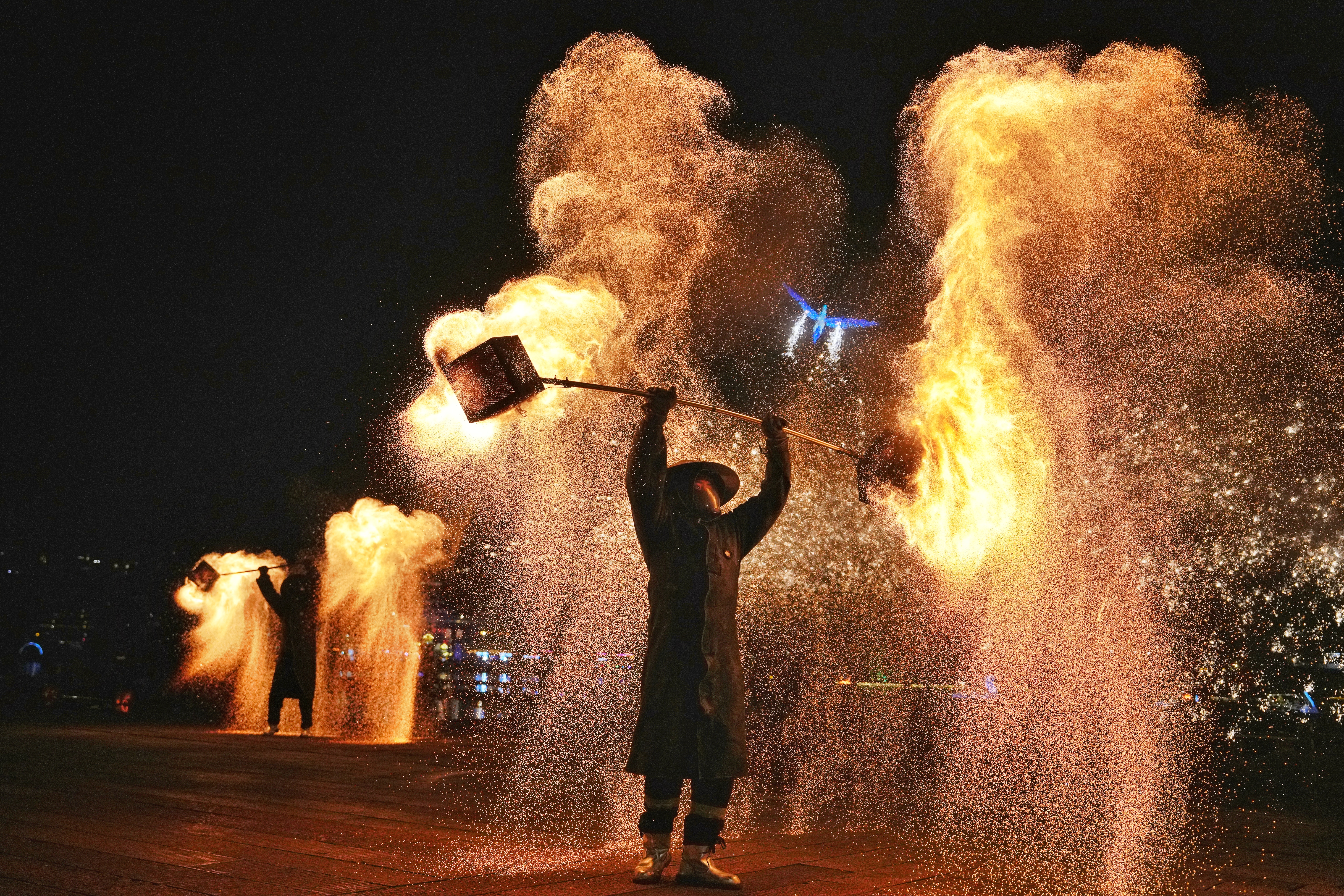 A folk artist performs the Huohu fire pot show, shaking an iron net with hot charcoals to create sparks.