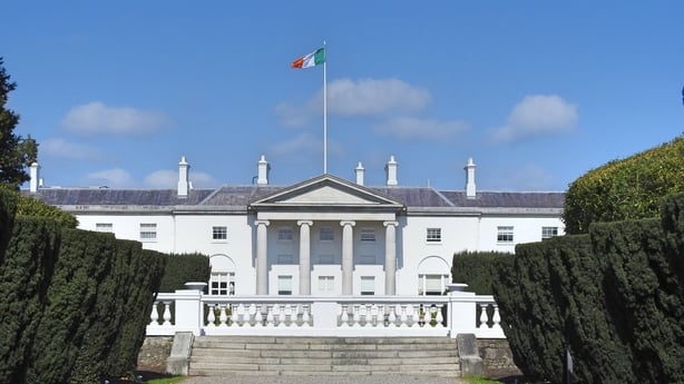 A photo of Aras an Uachtarain, with the Irish flag above and blue skies 