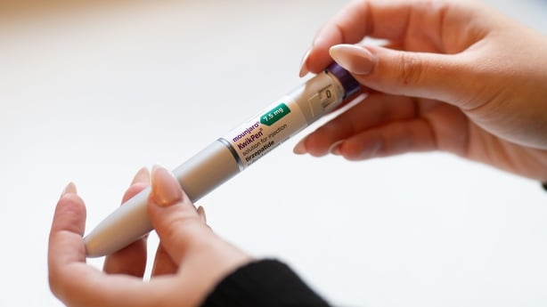A woman holds an injection pen