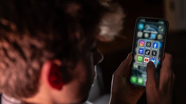 In this photo illustration a teenage boy looks at an iPhone screen displaying various social media apps 