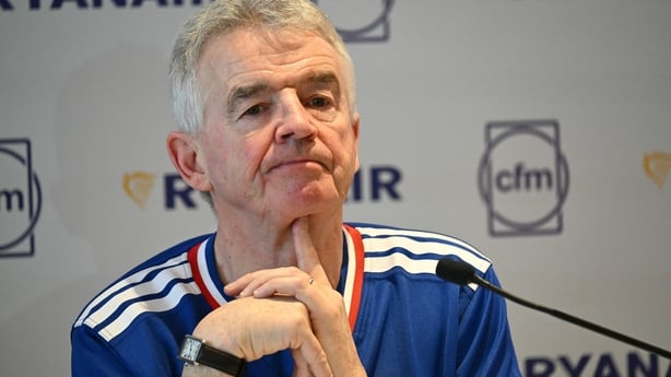 Business man in a rugby jersey sits at a press conference 
