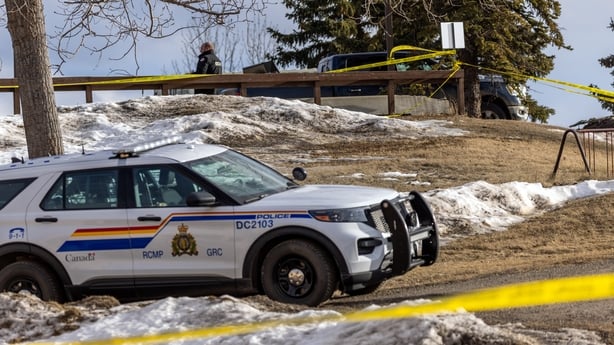 Crime scene tapes and a police car are seen with snow on the ground