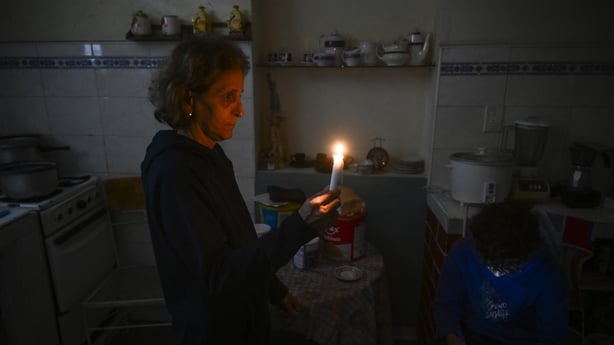A woman holds a candle while a boy checks his cellphone during a blackout in the Luyano neighborhood of Havana 