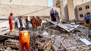 Rescuers search through the rubble of a collapsed building at the site of a strike on a neighborhood, in Tehran
