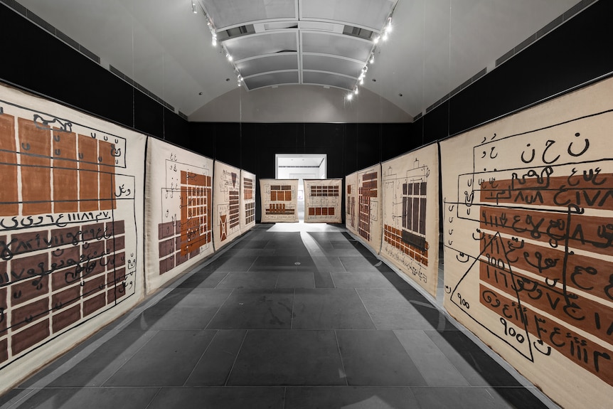 A room in which three walls are seen covered in different letters and number painted in brown paint.