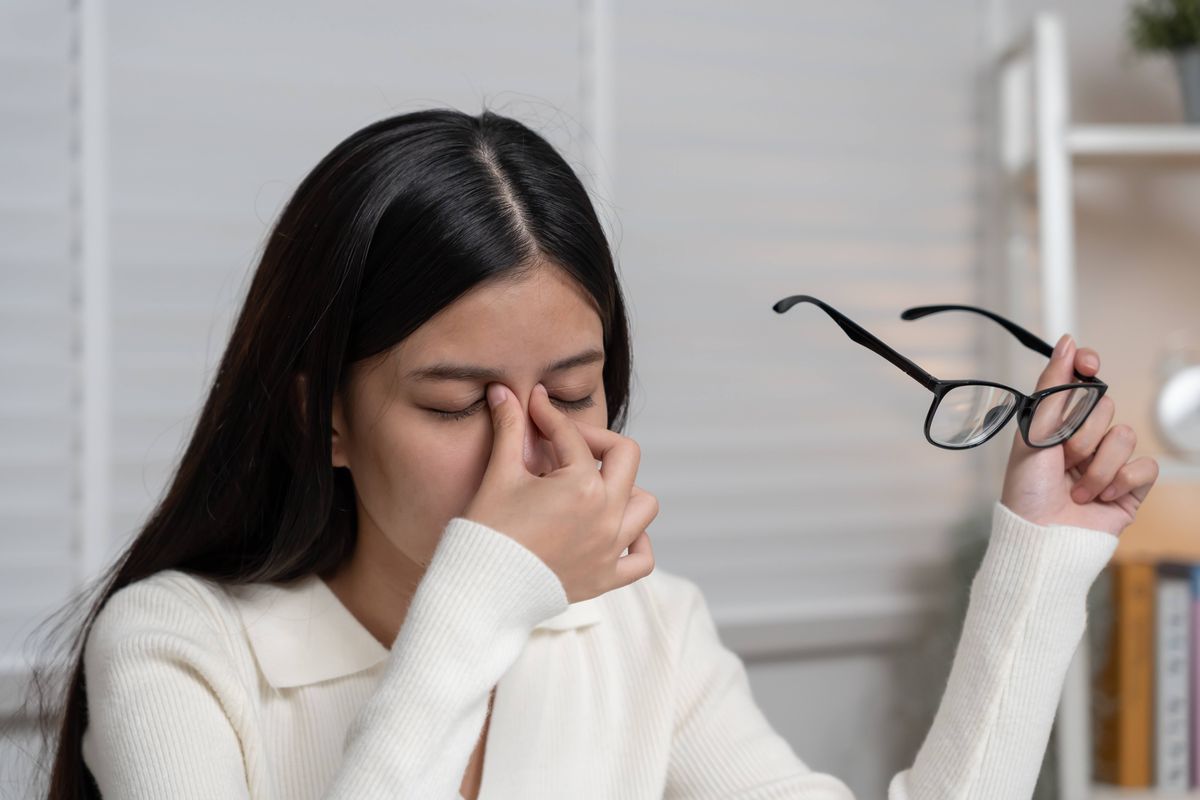 Eye problems, Asian women with tired and irritated eyes, eye rubbing, dry, eye pain after work, migraine, headache, blurred vision, photophobia, working in the dark, blue light from computer screens