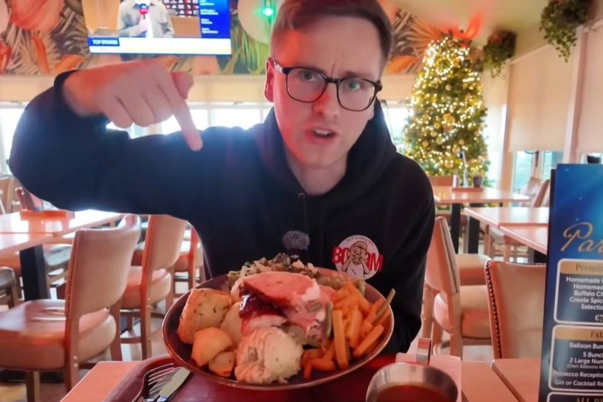 An individual seated at a table in a restaurant, holding a bowl filled with a variety of seafood, likely in the midst of dining.