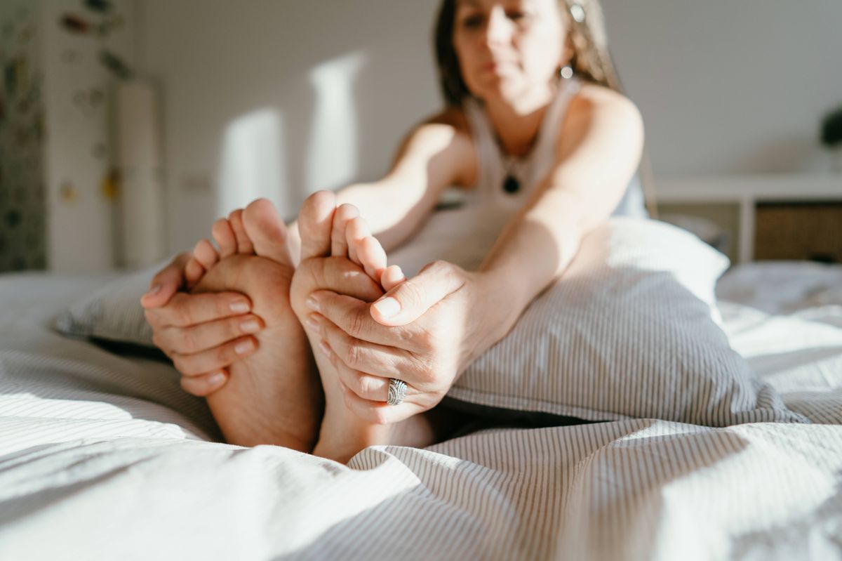 Woman at home, touching feet, generic