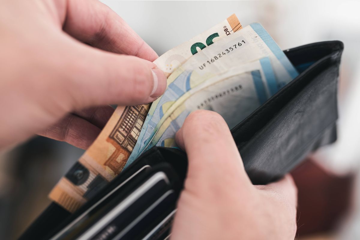 Close-up stock image of hands taking money out of a wallet