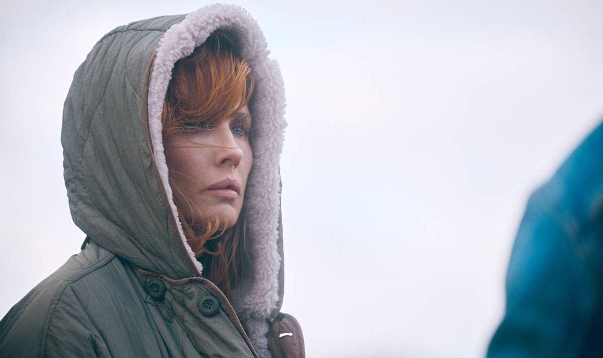 A woman in a hood looks serious