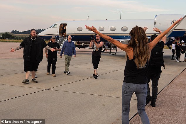The carousel of snaps show the singer - and his posse - getting off a private plane in South Dakota before greeting Noem with a large embrace and posing on the tarmac