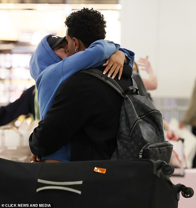 The pair couldn't keep their hands off each other as they kissed in the arrivals terminal