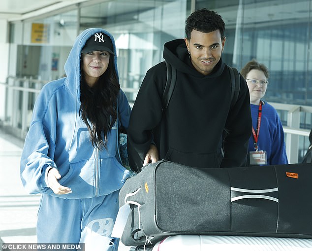 The couple linked arms as Harrison pushed a trolly stacked high with the couple's suitcases