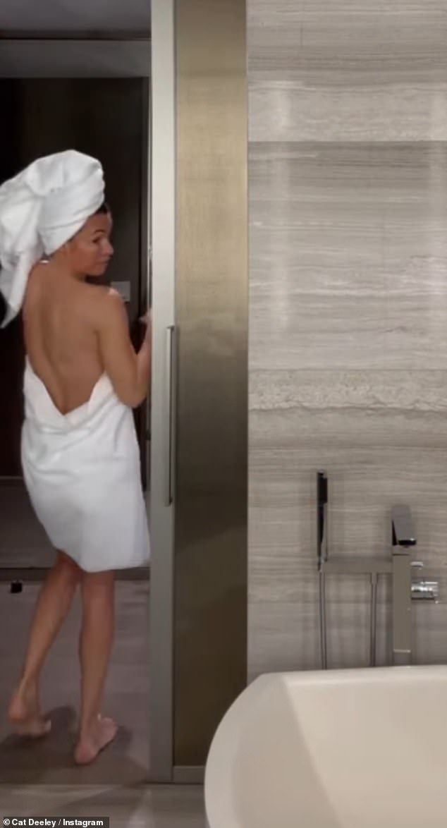 Wrapping her wet locks up in another plush white bathroom towel, Cat flashed a glimpse of her toned back, parading around the room
