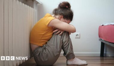 Sad lonely teen sitting on floor near smartphone and crying, feeling depressed.